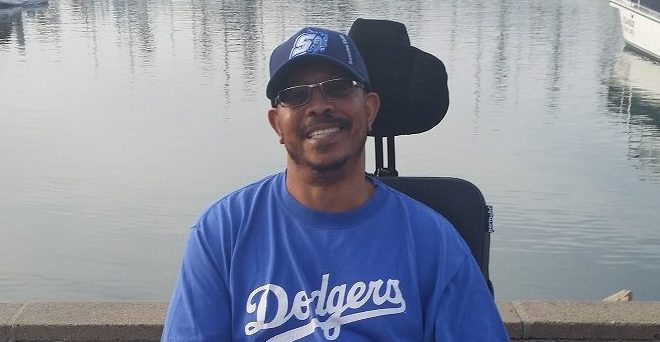 George A. Crockett, Jr. is seated in a wheelchair in front of a body of water.